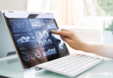 A tablet with attached keyboard displaying several different graphs of data. A person touches the tablet screen. To represent that HealthVerity launches taXonomy dataset for RWE research.