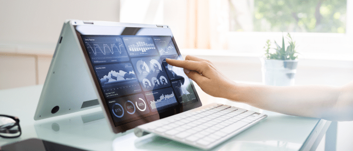 A tablet with attached keyboard displaying several different graphs of data. A person touches the tablet screen. To represent that HealthVerity launches taXonomy dataset for RWE research.